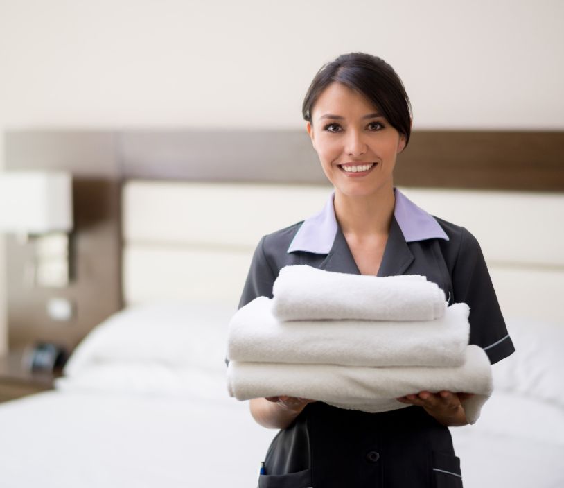A female hotel employee holding neatly folded linens illustrating laundry services in Fairfield NJ from Laundry Royalty