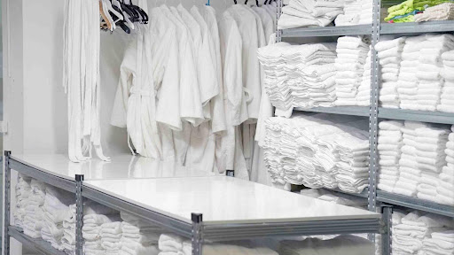 Shows a room filled with clean white towels and robes that were delivered through a local commercial laundry service in Northern NJ.